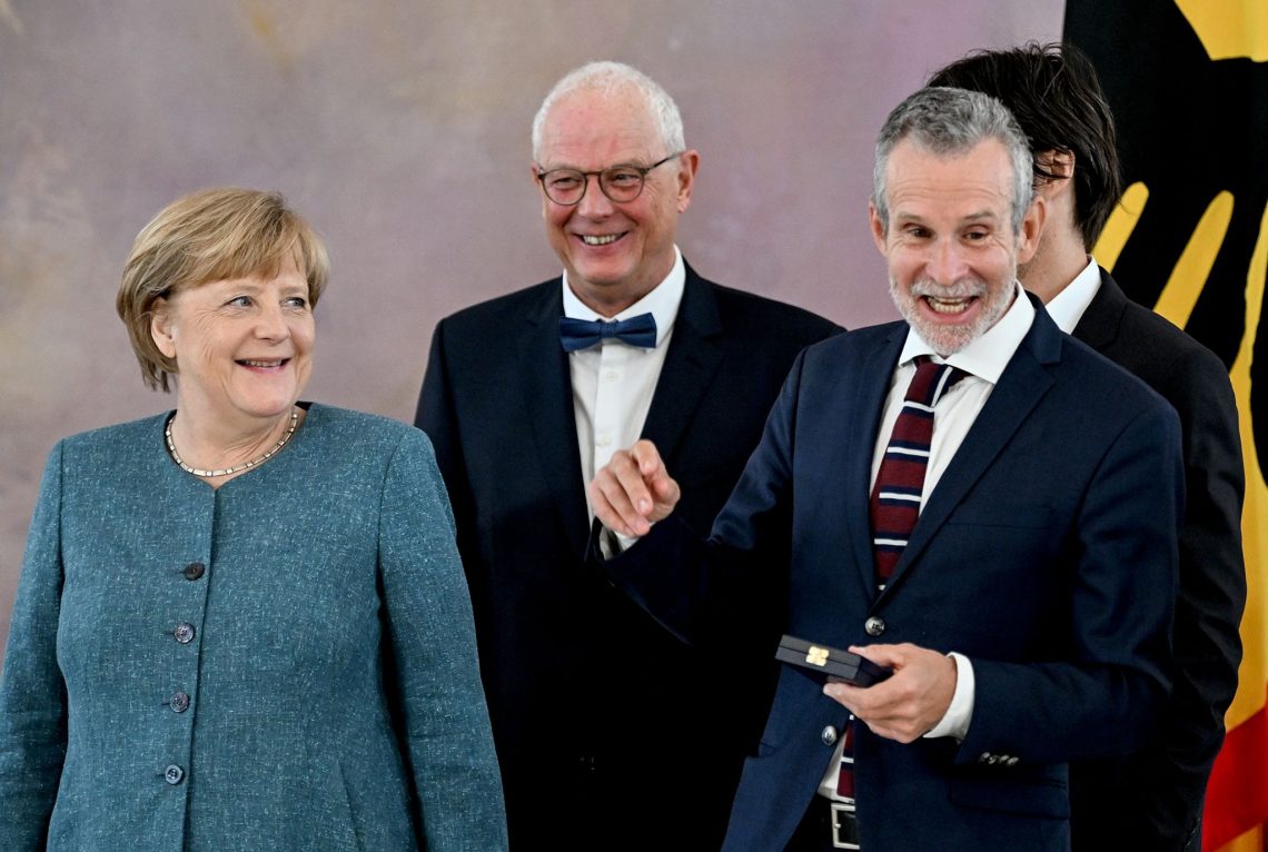 Angela Merkel (l-r), Autor Jean-Claude Kuner und der Verdienstkreuzträger  Ulrich Matthes im Schloss Bellevue.