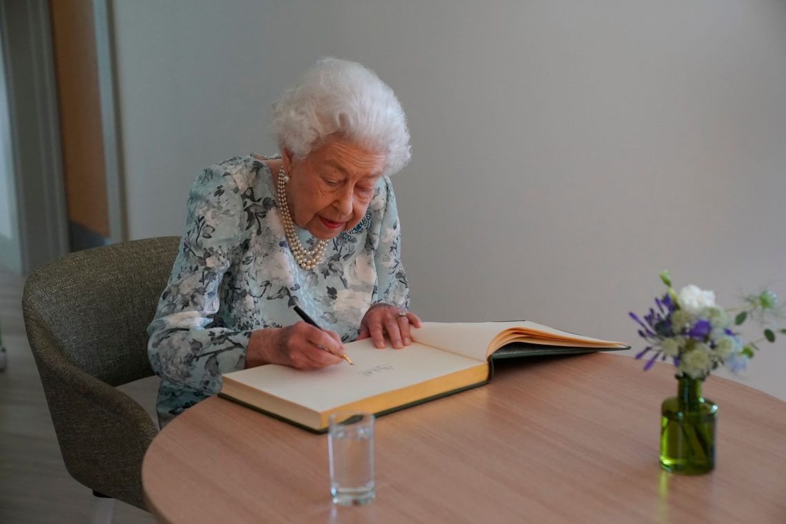Königin Elizabeth II. trägt sich im Thames Hospizins Besucherbuch ein.